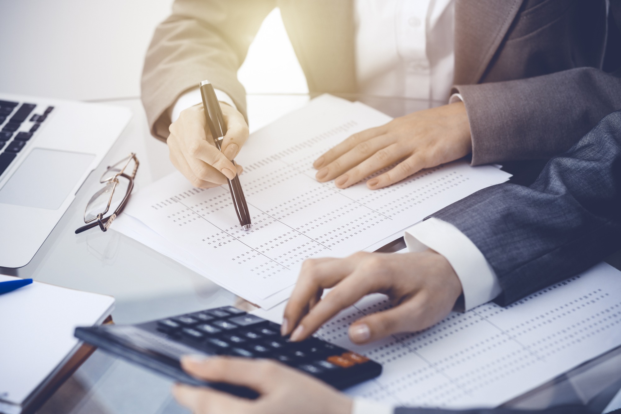 Two female accountants counting on calculator